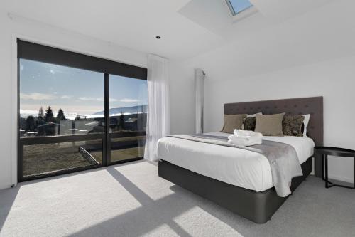 a bedroom with a large bed and a large window at Cardrona Vista Apartment in Cardrona