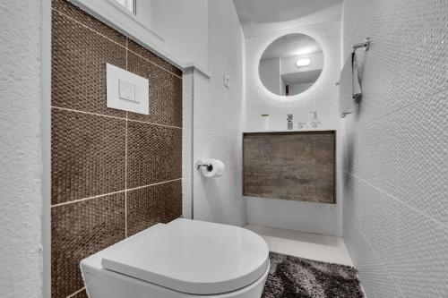 ein weißes Bad mit einem WC und einem Spiegel in der Unterkunft Apartments by the sea Makarska - 21443 in Makarska
