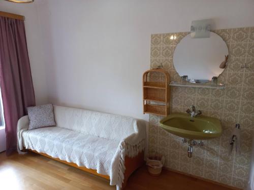 a bathroom with a couch and a sink and a mirror at Appartements direkt am See in Grundlsee
