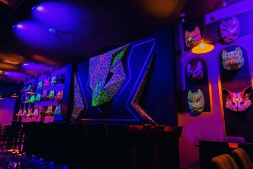 Habitación con luces y máscaras púrpuras en la pared en Hotel Yoru en Querétaro