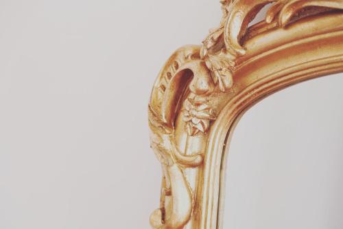 an ornate gold mirror on a white background at La Bâtisse en Blanc in Golfe-Juan