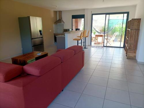 a living room with a red couch and a kitchen at Beau T3 proche plage secteur Montabo à Cayenne in Cayenne