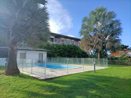 una valla alrededor de una piscina con 2 palmeras en Beau T3 proche plage secteur Montabo à Cayenne en Cayenne