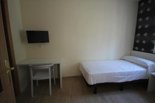 a bedroom with a bed and a desk and a tv at Pension los Arcos in Los Arcos