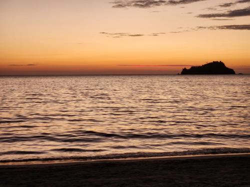 a sunset on the beach with a rock in the water at Edificio Macondo en el Rodadero con vista al mar, NO se paga manilla in Rodadero