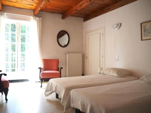 een slaapkamer met 2 bedden, een stoel en een spiegel bij holiday home, Pont-Saint-Esprit in Pont-Saint-Esprit