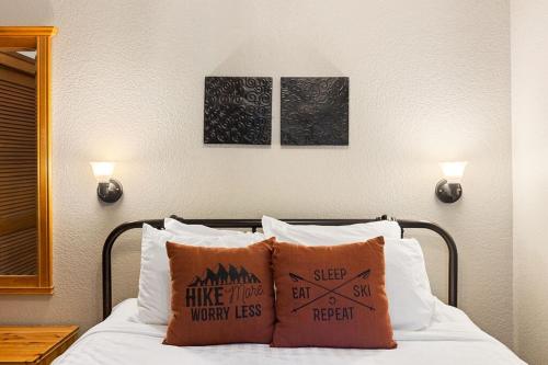 1 cama con 2 almohadas y 2 cuadros en la pared en LOGE Alta Crystal Resort at Mt Rainier en Enumclaw