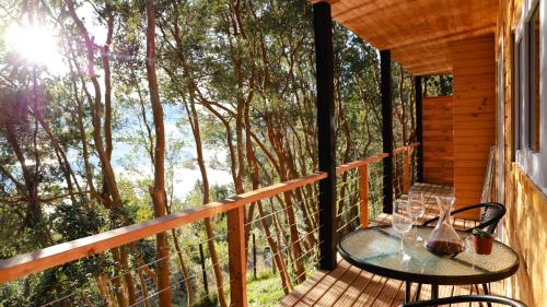 a patio with a table and chairs on a deck with trees at Cabañas Loft Alto Arrayan Cochamó in Cochamó