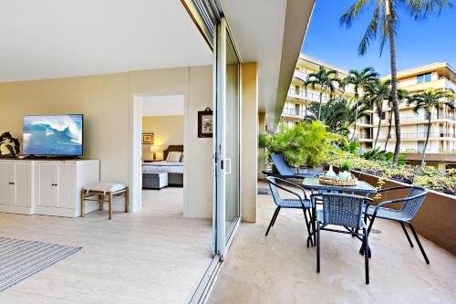 Maui Kaanapali Villas A209 في كانابالي: فناء مع طاولة وكراسي وغرفة معيشة
