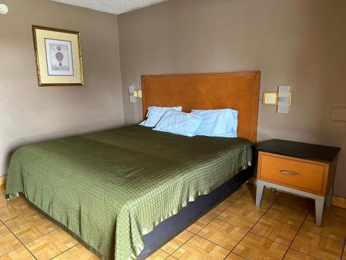 a bedroom with a bed and a nightstand with a green blanket at Lone Star Inn & Suites in Harlingen