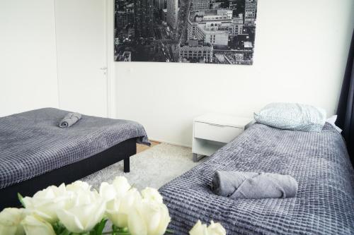 a bedroom with two beds and a vase of white flowers at 3-Room Central Railway station in Oulu