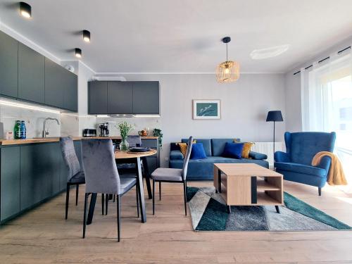 uma cozinha e sala de estar com um sofá azul e uma mesa em CLASSY APARTMENTS - AQUAPARK Reda Novum em Rumia