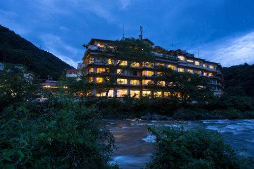 a large building next to a river at night at Hakone Yumoto Onsen Hotel Kajikaso in Hakone