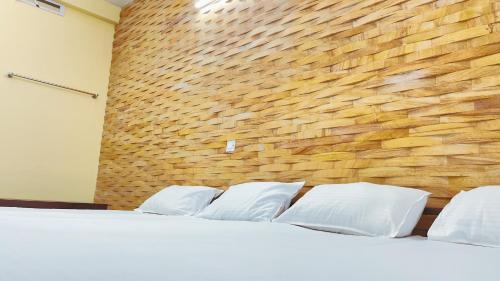 uma cama com almofadas brancas contra uma parede de tijolos em PPG HOMES em Ernakulam