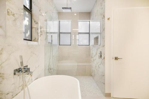 y baño blanco con ducha y bañera. en Villa RendezVous- Stunning 4BDR with Pool by VIAC, en Fort Lauderdale