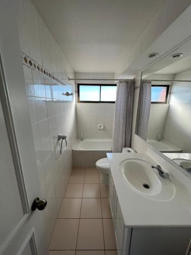 ein weißes Badezimmer mit einem Waschbecken und einer Badewanne in der Unterkunft Departamento con insuperable vista Playa Amarilla Playa La Boca in Concón