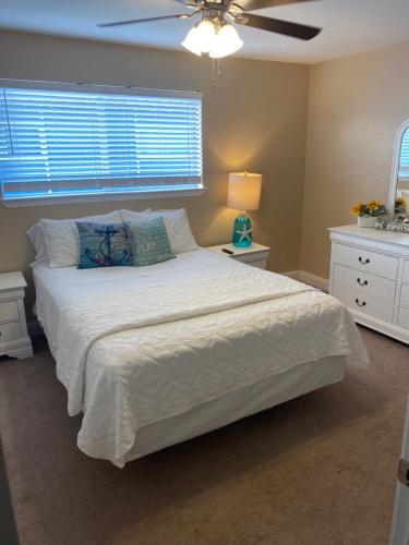 a bedroom with a white bed with a ceiling fan at Oak Shores. in Biloxi