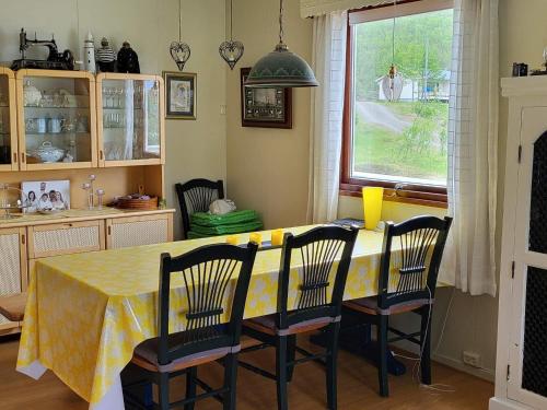 a dining room table with chairs and a yellow table cloth at Holiday home Reinfjord in Spildra
