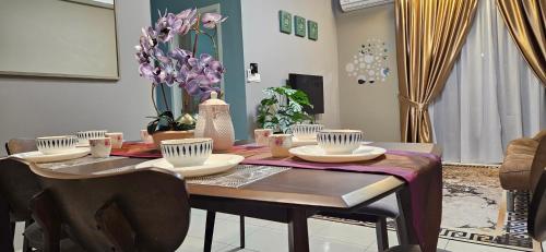 a dining room table with dishes and flowers on it at E. R Homestay 3R2B nearby KLIA in Sepang