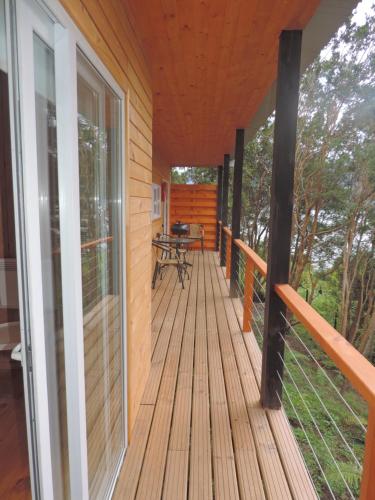 a wooden deck with a table on it at Cabañas Loft Alto Arrayan Cochamó in Cochamó