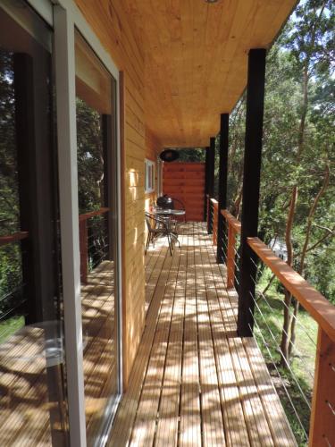 a wrap around porch of a house with glass doors at Cabañas Loft Alto Arrayan Cochamó in Cochamó