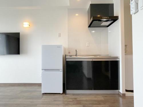 a kitchen with a white refrigerator and a sink at New Normal Hotel in NAMINOUE ニューノーマルホテルイン波の上 in Naha
