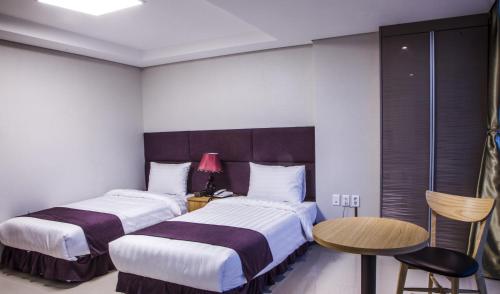 a hotel room with two beds and a table and a chair at J Hotel in Ulaanbaatar