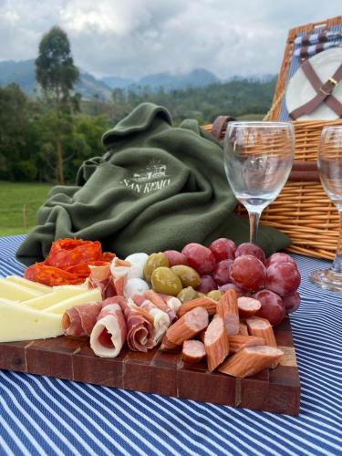 a wooden cutting board with meats and cheese on a table at Hotel Rural SAN REMO in Santa Rosa de Cabal