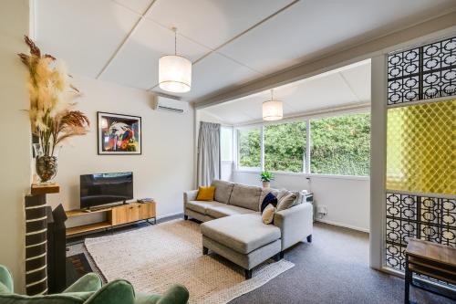 a living room with a couch and a tv at Central Cottage - Napier Holiday Home in Napier