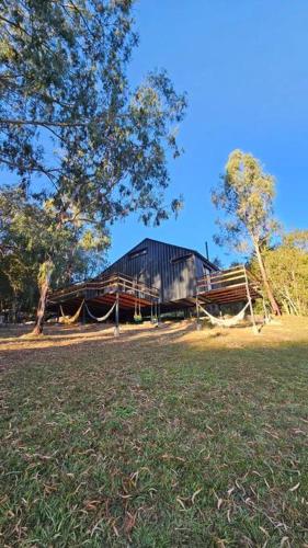 a black building with a tree and a grass field at Complejo de Cabañas Eco-sustentables - La escondida - in San Salvador de Jujuy