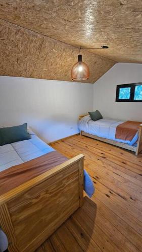 1 dormitorio con 2 camas y suelo de madera en Cabaña La escondida - JuJuy- en San Salvador de Jujuy