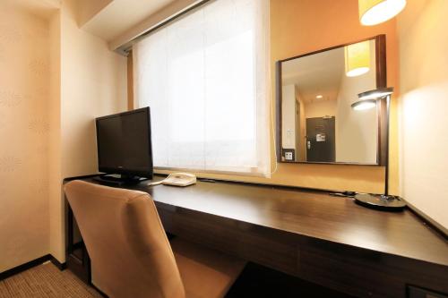 a desk with a television and a mirror at Via Inn Kanazawa in Kanazawa