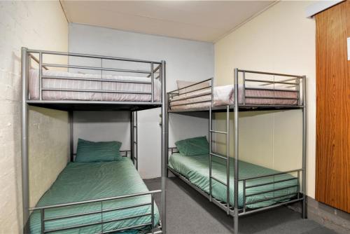 2 Etagenbetten in einem Zimmer mit grüner Bettwäsche in der Unterkunft Espanola 1 in Long Jetty
