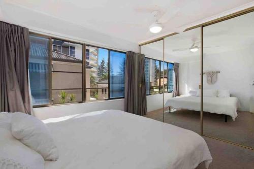 1 dormitorio con cama blanca y ventana grande en ON THE BEACH AT RAINBOW BAY, en Gold Coast