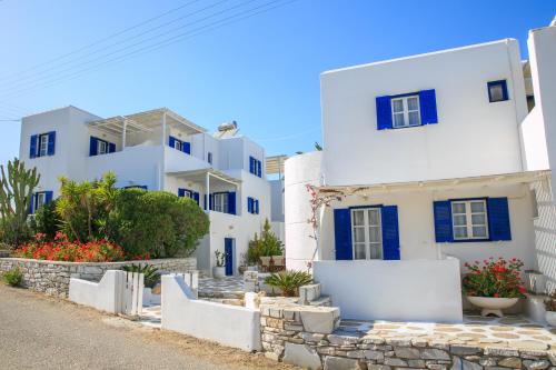 a row of white houses with blue windows at Nicos Studios & Apartments in Logaras