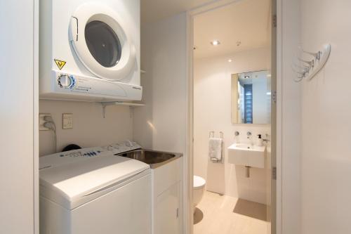 y baño blanco con lavabo y lavadora. en Cable Bay Luxury 1 Bedroom Surf Villa, en Cable Bay
