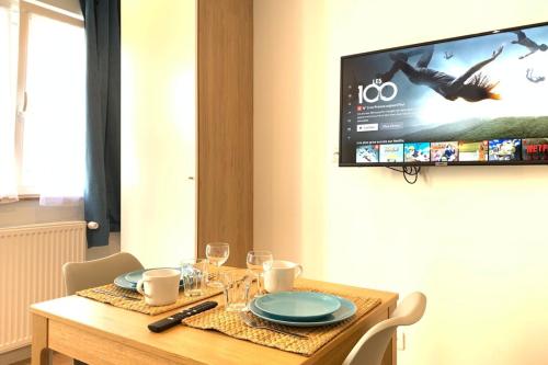 een eettafel met een televisie aan de muur bij M2 Cosy studio RER BC500m Orly 20 min Netflix in Massy