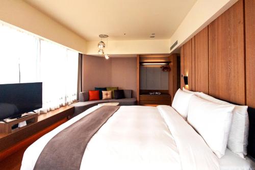 a large white bed in a room with a couch at Yamagata Kaku Hotel & Spa in Jiaoxi