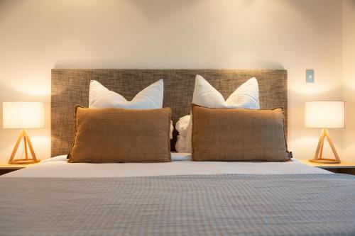 1 dormitorio con 1 cama con almohadas y 2 lámparas en Cable Bay Luxury 1 Bedroom Surf Villa, en Cable Bay