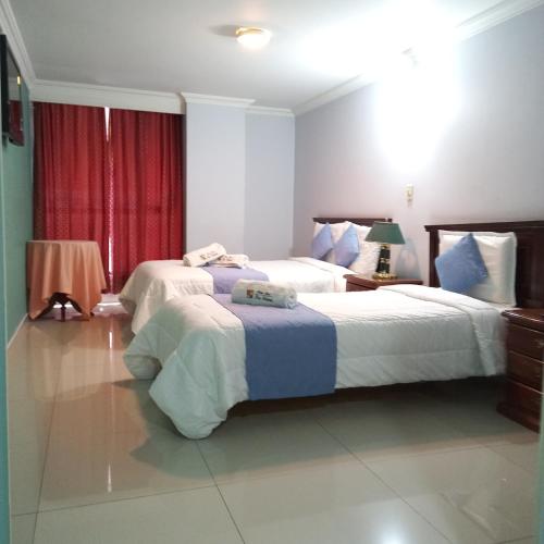 a bedroom with two beds and a red curtain at HOTEL REALPICO VICTORIA in Duitama