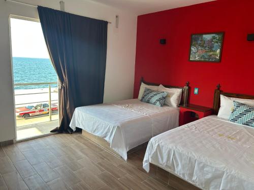 two beds in a room with a red wall at Hotel Jar8 Bule in Boca del Río