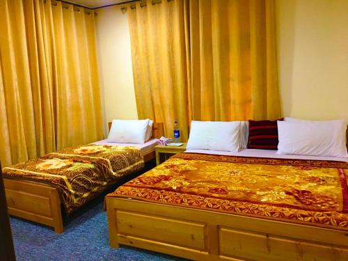two beds in a room with yellow curtains at Chitral Inn Resort (Kalash Valley) in Chitral