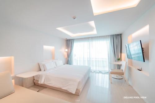 um quarto branco com uma cama e uma janela em Prima Hotel Pattaya em North Pattaya