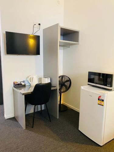 a room with a desk with a chair and a refrigerator at Gamma Hotel in Auckland