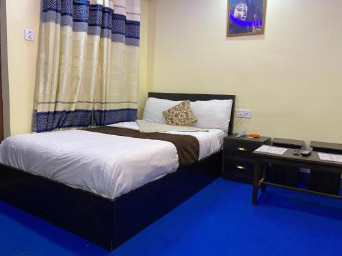 um quarto com uma cama e uma mesa de cabeceira com uma cama sidx sidx em Hotel Yog Darshan em Kathmandu