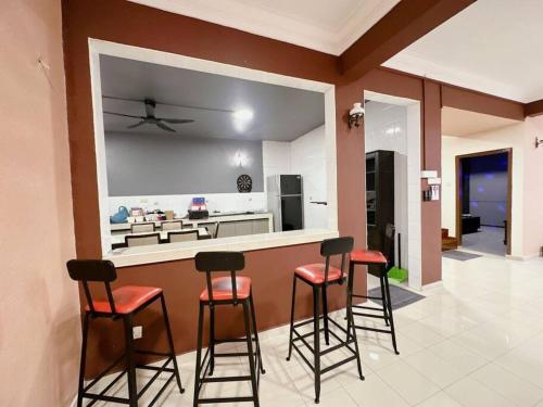 una cocina con una barra con 4 taburetes en B04 Modern Deluxe Homestay, en Johor Bahru