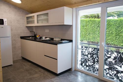 a kitchen with white cabinets and a sliding glass door at Nordés Apartamentos Turísticos - Bañugues in Bañugues
