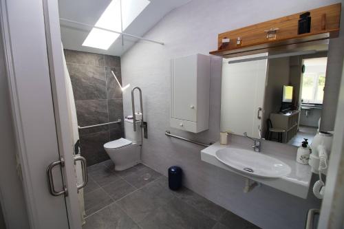 a bathroom with a sink and a toilet at Nordés Apartamentos Turísticos - Bañugues in Bañugues