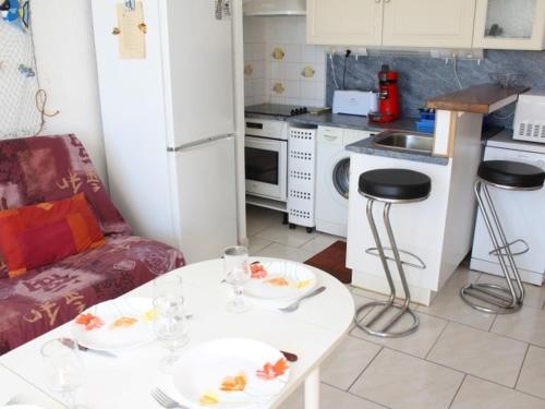 Elle comprend une petite cuisine avec une table blanche et un réfrigérateur blanc. dans l'établissement Appt 2P cabine, 6 couchages avec piscine et parking à Gruissan, près plage et port - FR-1-229-868, à Gruissan