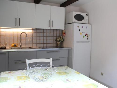 une cuisine avec des armoires blanches et un réfrigérateur blanc dans l'établissement Pavillon près plage pour 4 pers. avec terrasse, parking et wifi, animaux acceptés - Gruissan - FR-1-229-869, à Gruissan